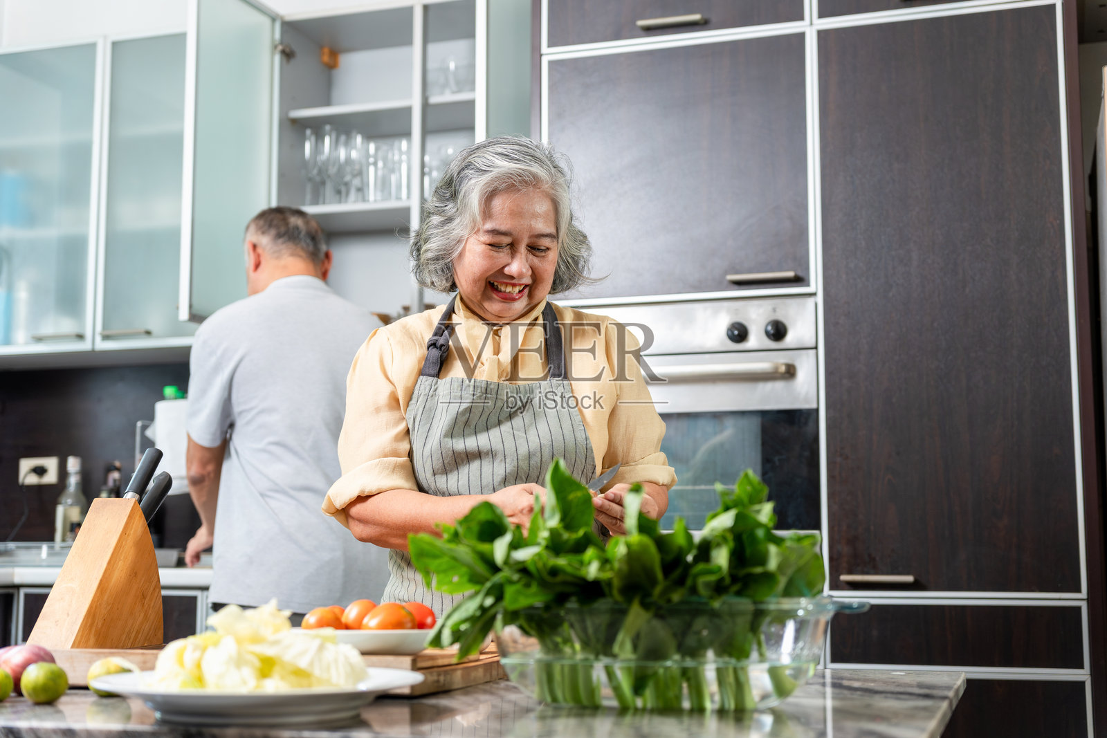 快乐的亚洲老年夫妇在厨房一起烹饪健康餐，年长的亚洲配偶为晚餐准备新鲜蔬菜，成熟的夫妇在家享受烹饪，健康生活方式照片摄影图片