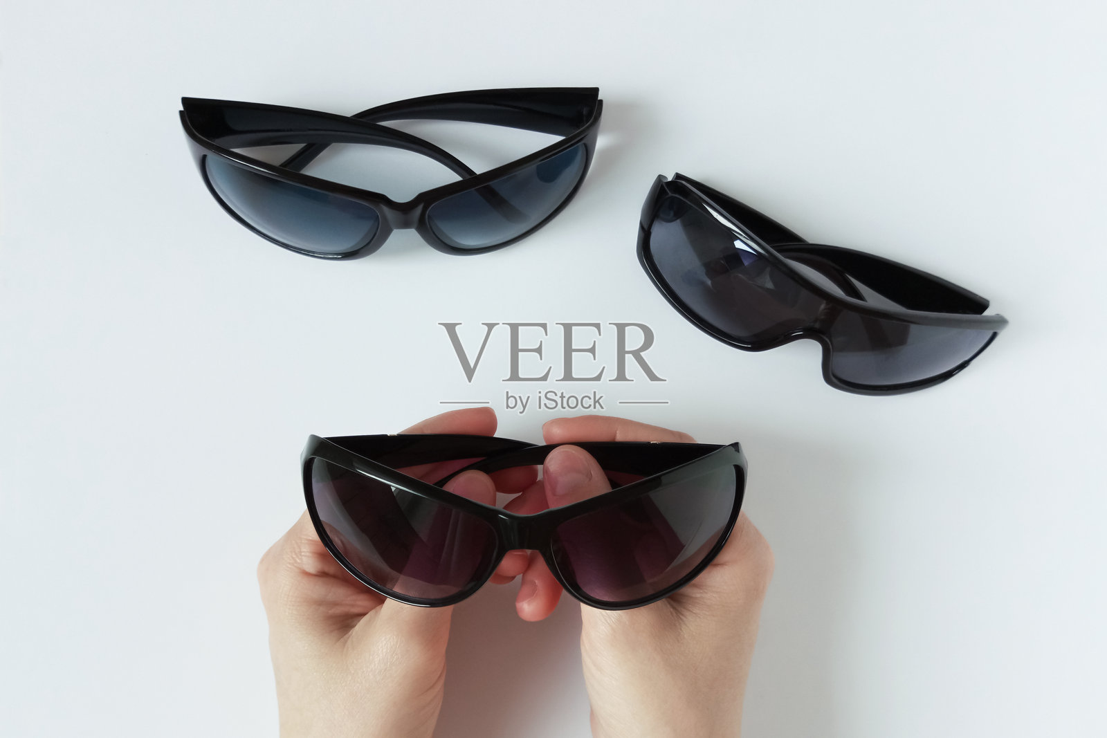 一位白人女性手中拿着黑框太阳镜，正在挑选眼镜。照片摄影图片