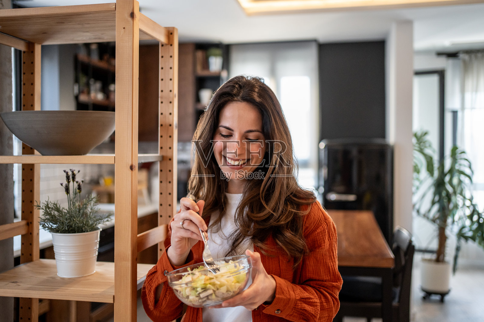 微笑的女性在现代厨房中享用新鲜沙拉照片摄影图片