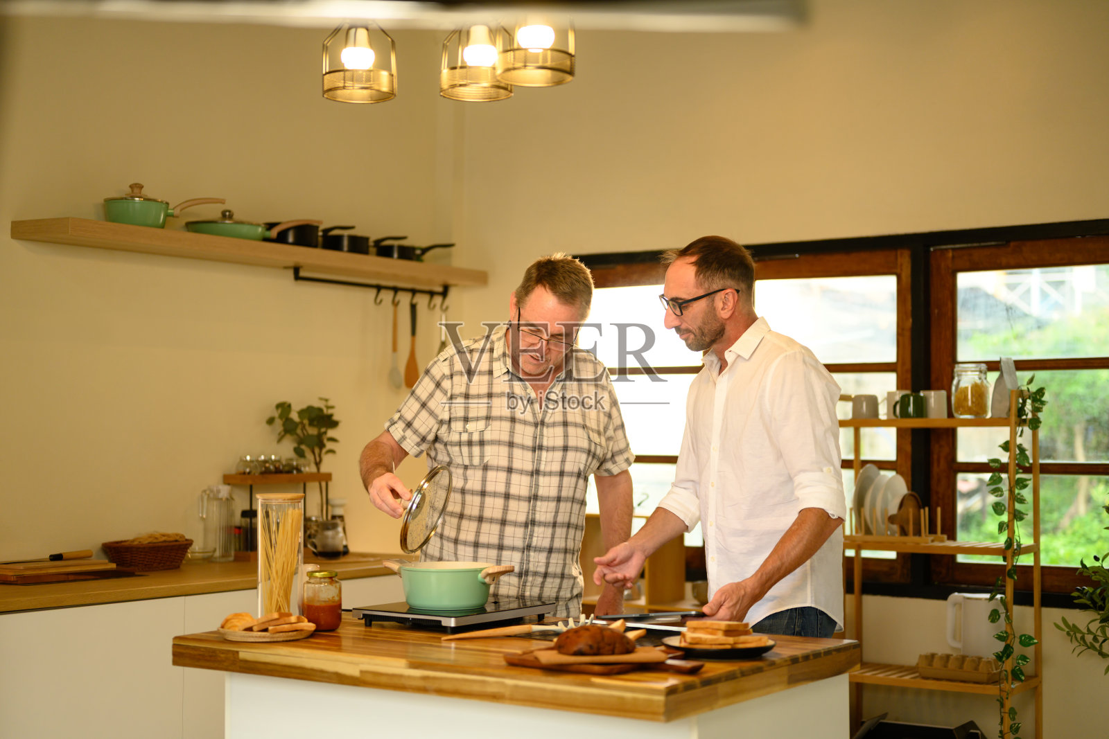 父亲和儿子在家里的厨房享受烹饪新鲜的自制菜肴。父亲节概念照片摄影图片