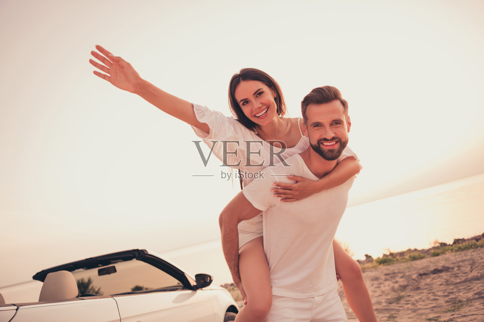 无忧无虑的搞笑夫妻穿着休闲服装，驾驶敞篷车，享受阳光明媚的户外海滩时光。照片摄影图片
