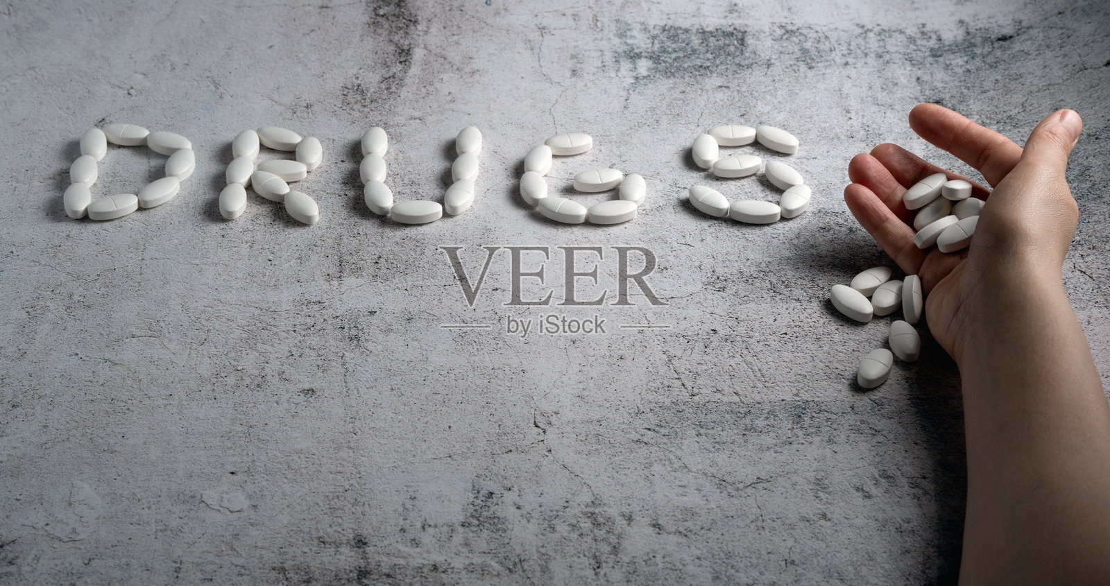 手握药丸，旁边用药片拼写的“药物”照片摄影图片