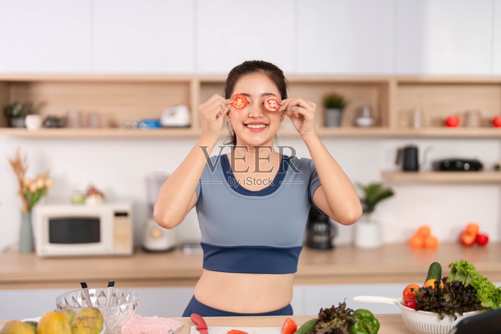 ESG与健康生活方式。女人顽皮地将番茄片放在眼前。照片摄影图片