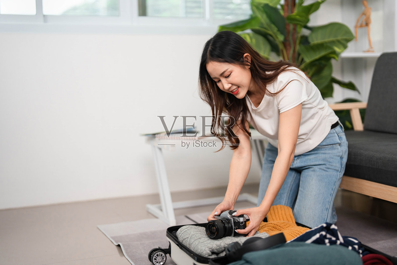 冒险打包必备品。年轻女性兴奋地整理她的行李箱。照片摄影图片