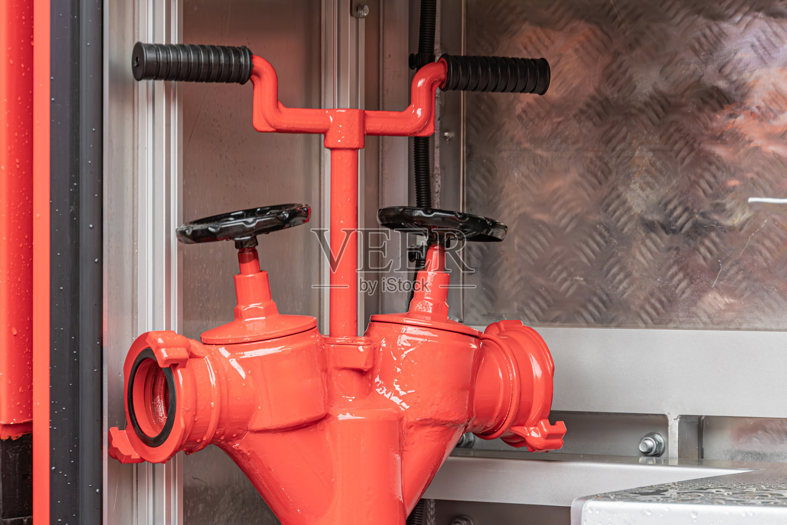 工业环境中红色管道组件的特写图像，附有阀门，自然光在右侧投射出柔和的阴影。照片摄影图片