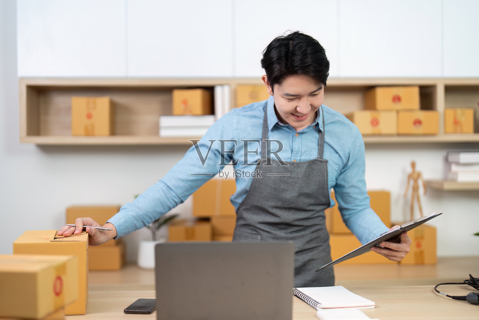 年轻企业家在现代工作空间中管理物流，打包和贴标签箱子。照片摄影图片