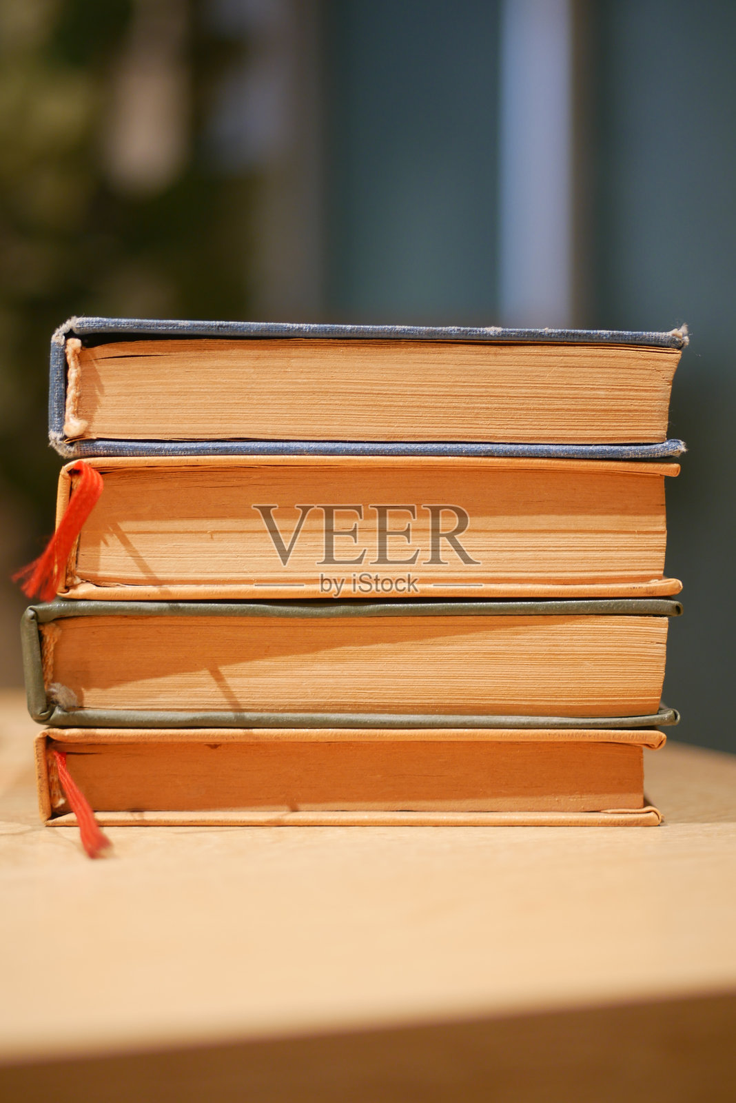 堆叠在木桌上的复古书籍，书脊呈现多种颜色照片摄影图片
