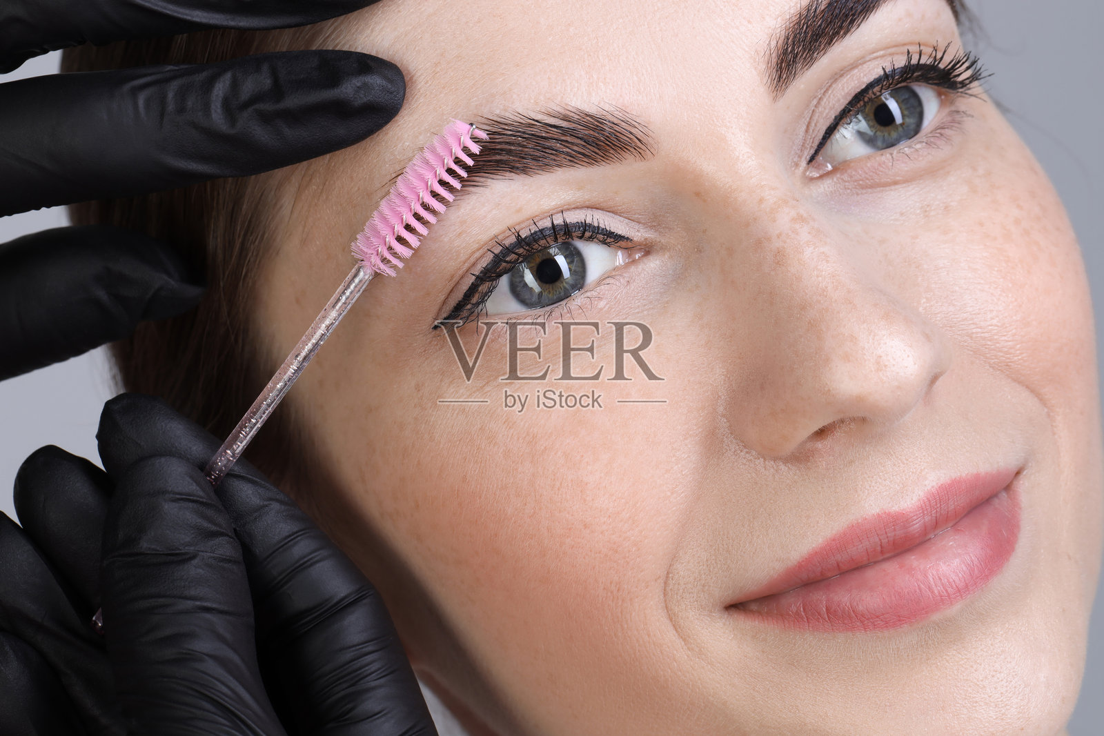 眉毛定型。美容师用刷子梳理女性的眉毛，特写镜头照片摄影图片