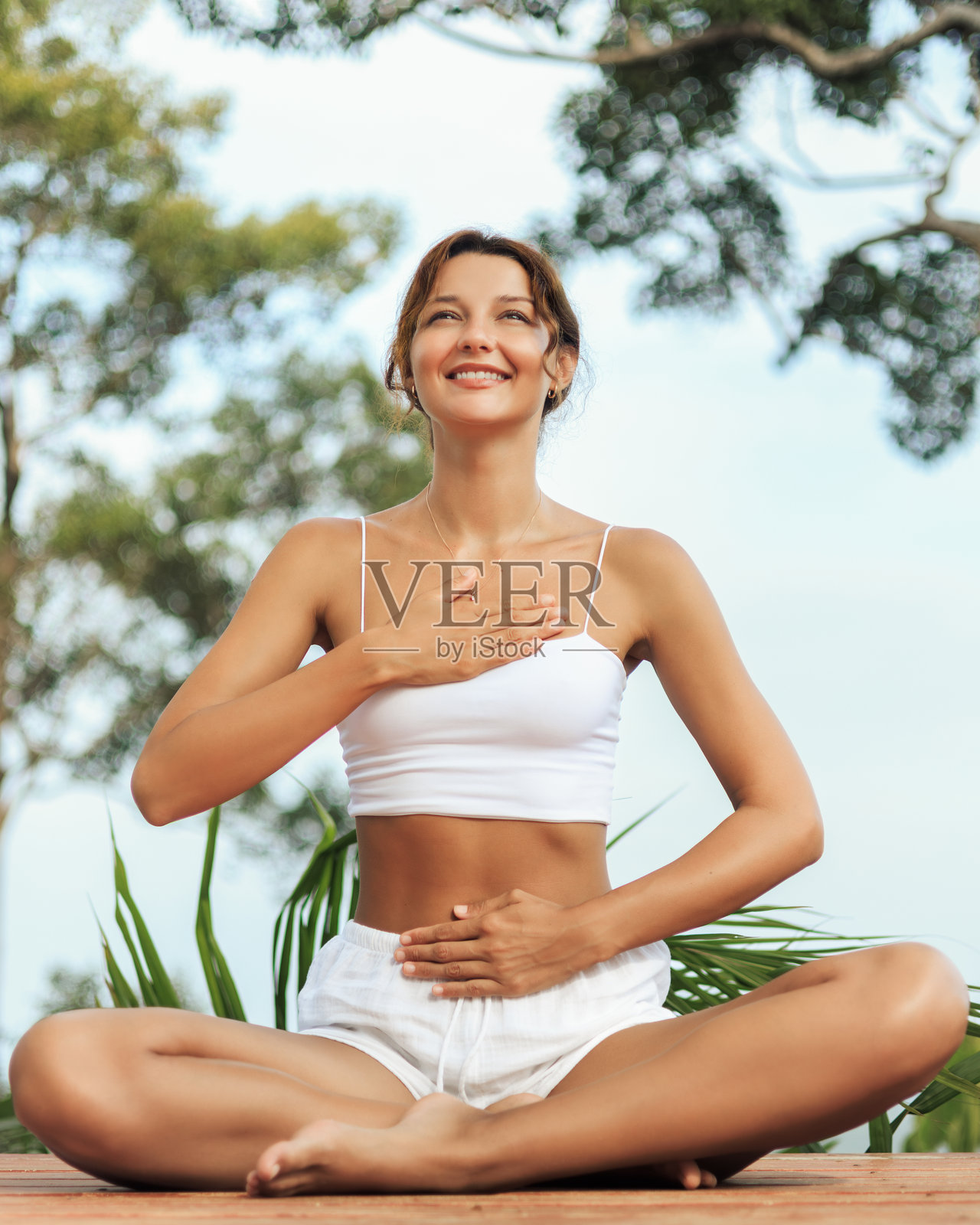 微笑的女性在户外练习呼吸法，双手放在心口和腹部上照片摄影图片