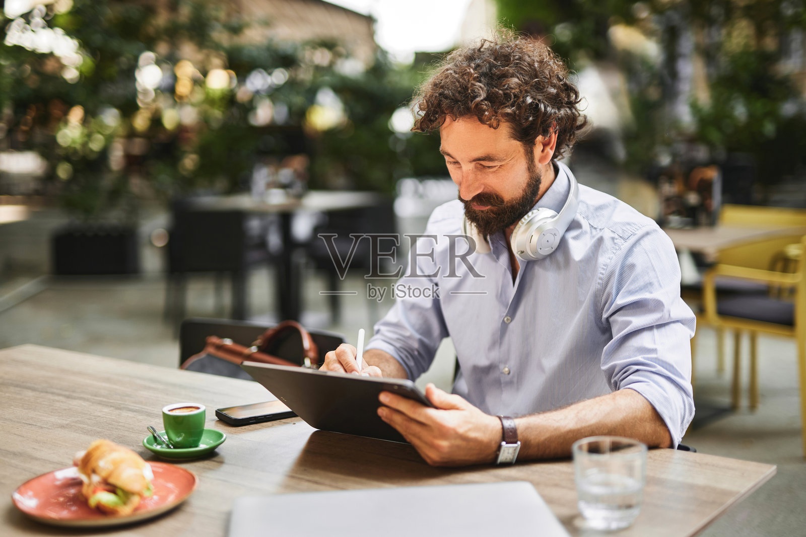 在咖啡馆远程工作的商人使用数字平板电脑照片摄影图片