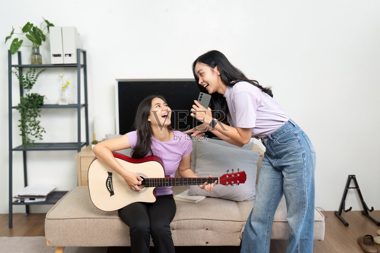 音乐乐趣。两个朋友在家享受热闹的即兴演奏。照片摄影图片