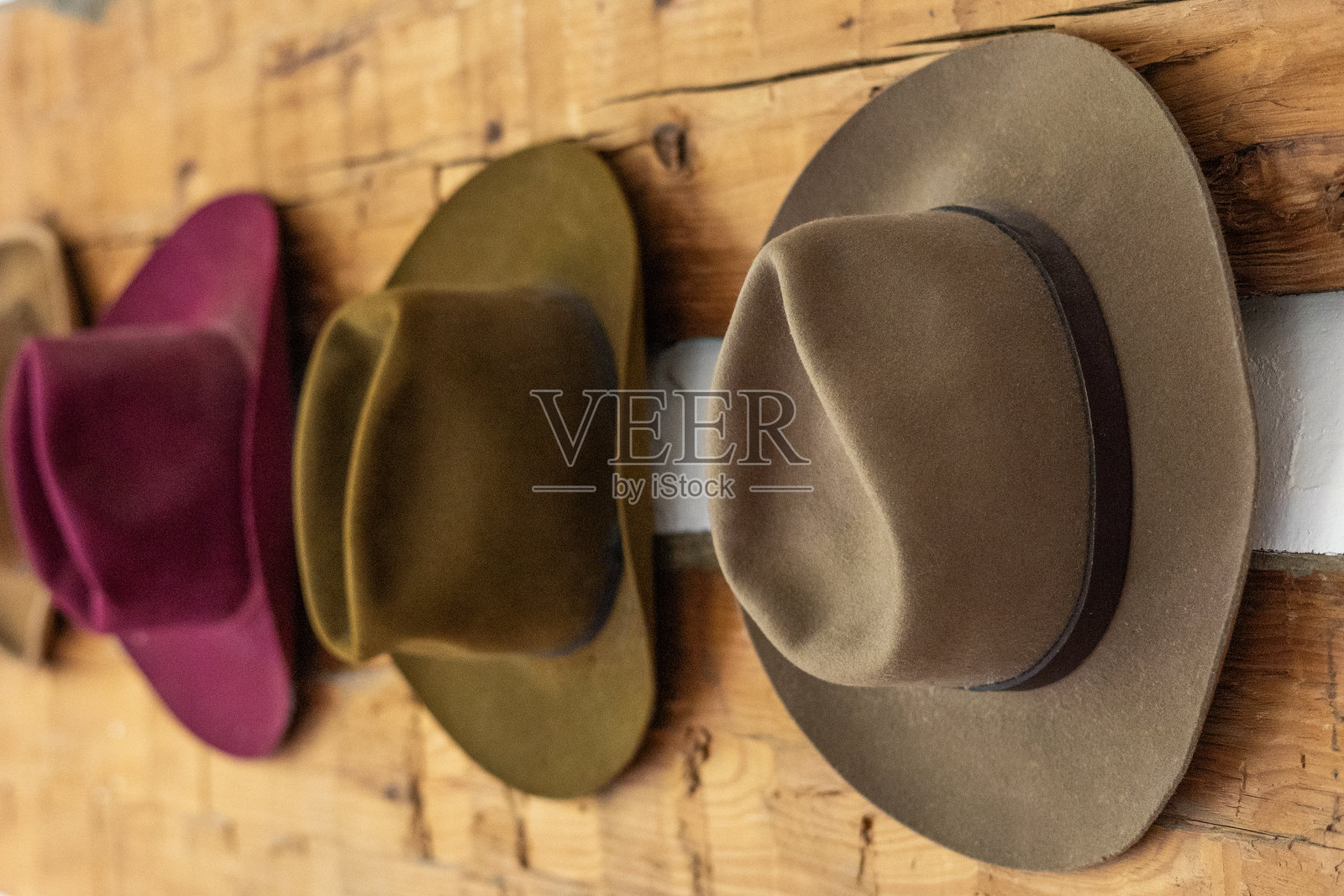 毛毡牛仔帽挂在质朴的木墙上照片摄影图片