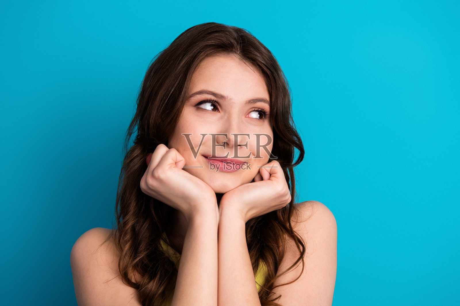 年轻迷人的女性在鲜艳的蓝色背景前摆姿势，展现迷人的表情照片摄影图片