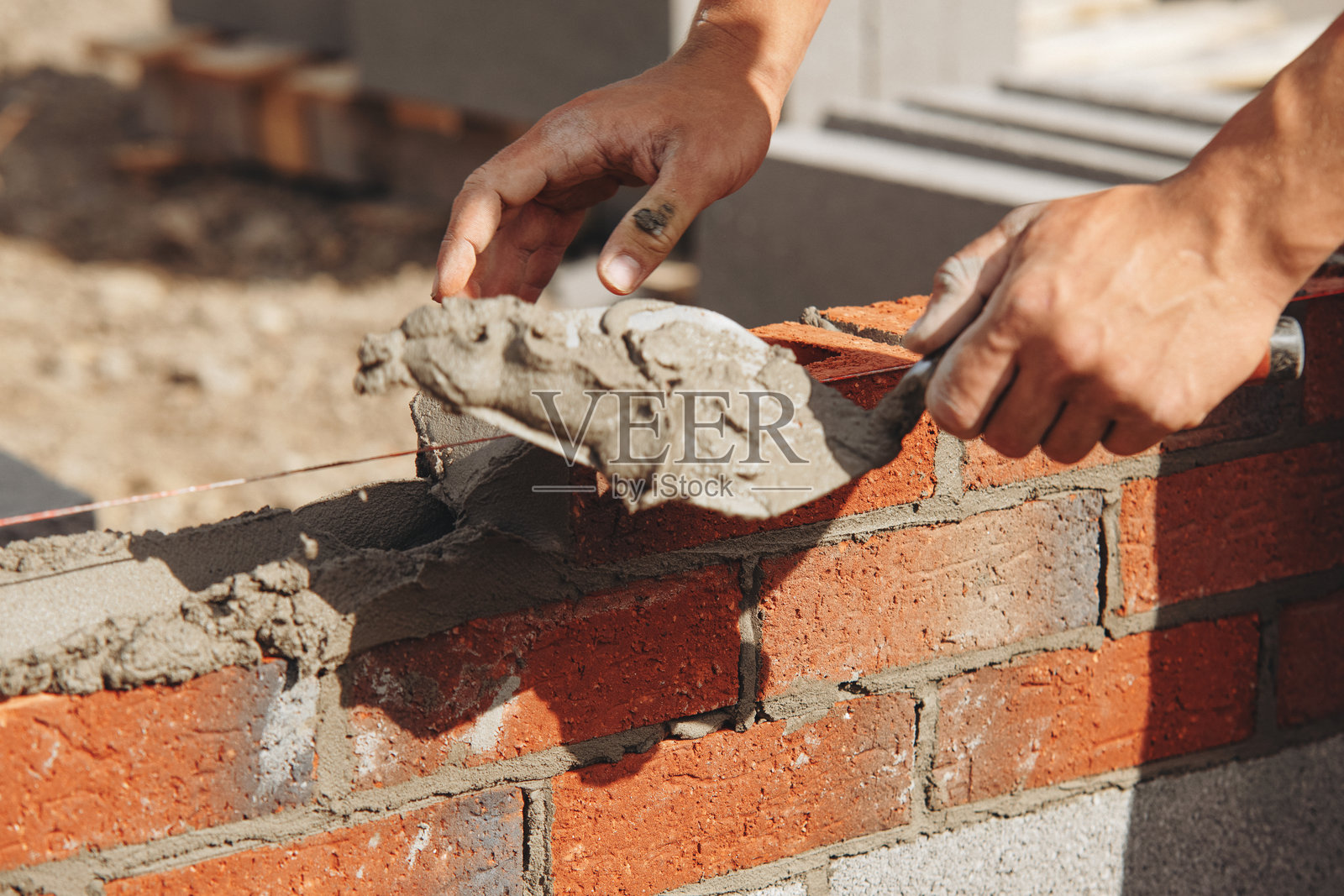 熟练工人在建筑工地上用抹子铺砖的特写镜头照片摄影图片