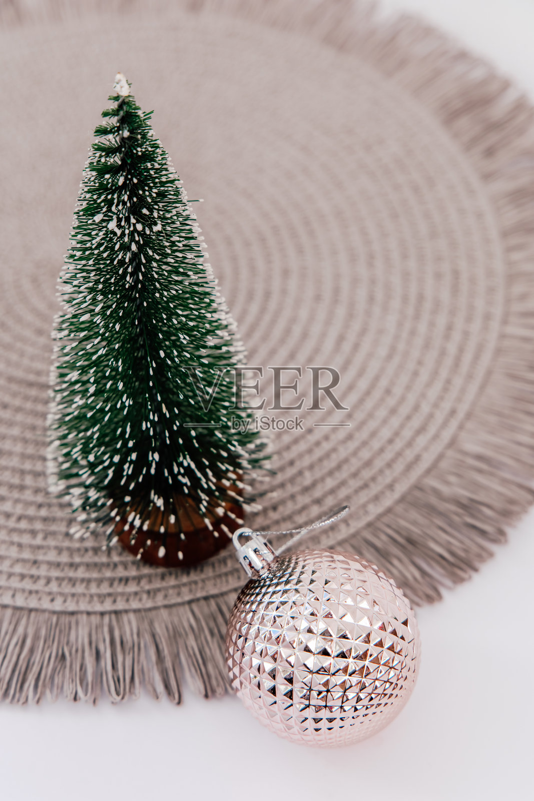 装饰性的节日布置，包含一棵小树和一个闪亮的装饰品，放在圆形垫子上照片摄影图片