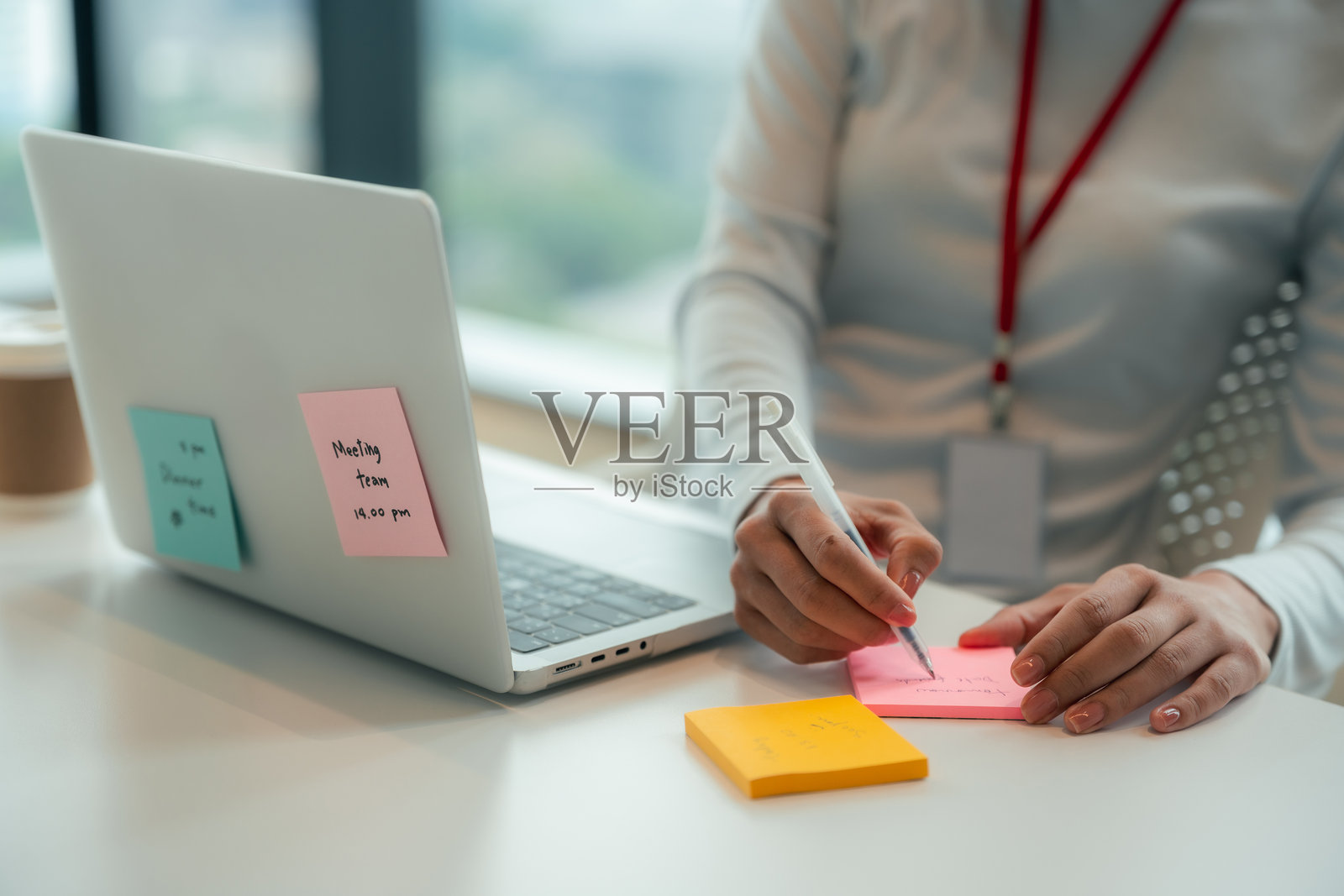 商务女性在现代办公室使用笔记本电脑，粘性便签贴在显示器上。照片摄影图片