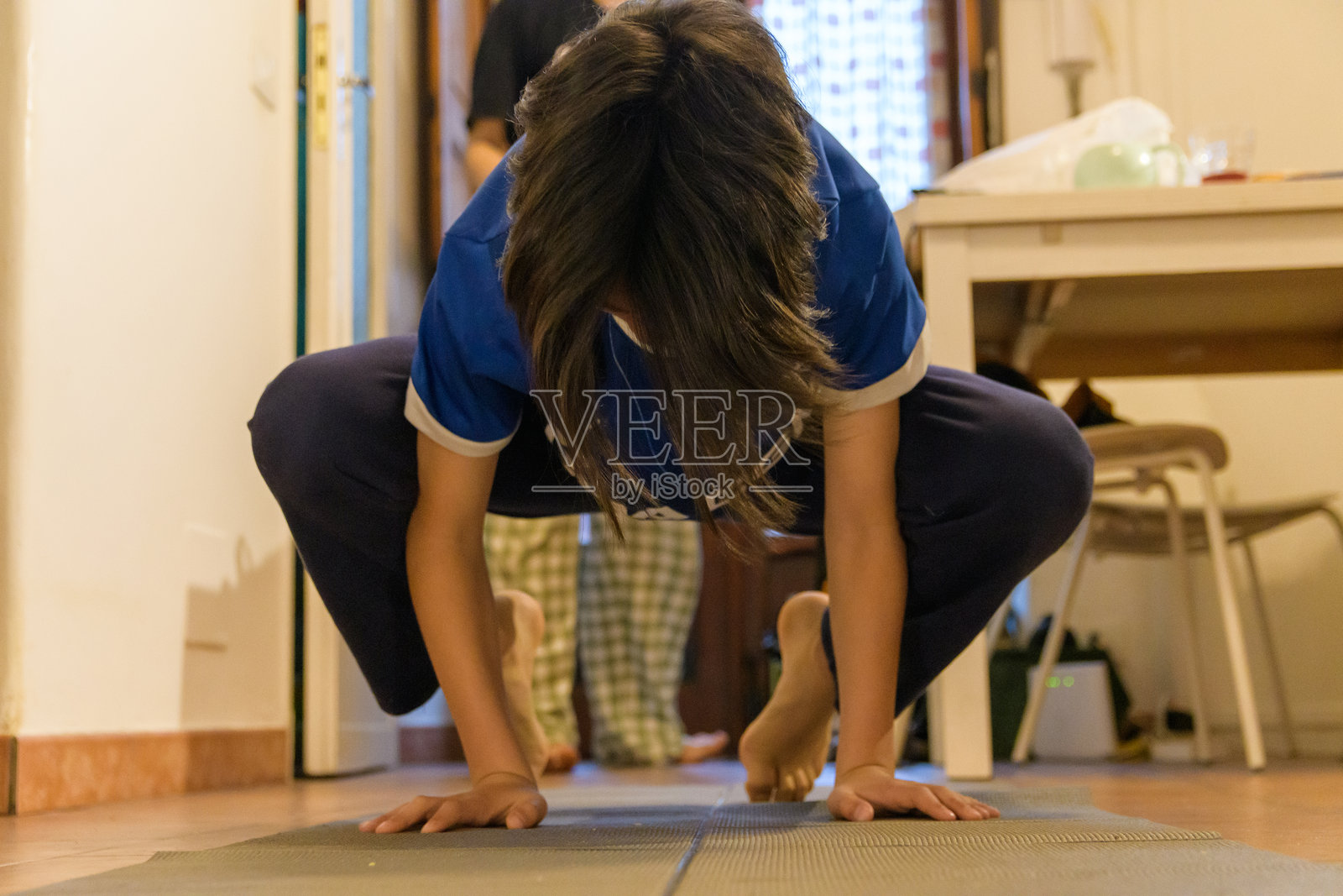 在家中练习瑜伽的少年男孩，摆出花环式姿势照片摄影图片