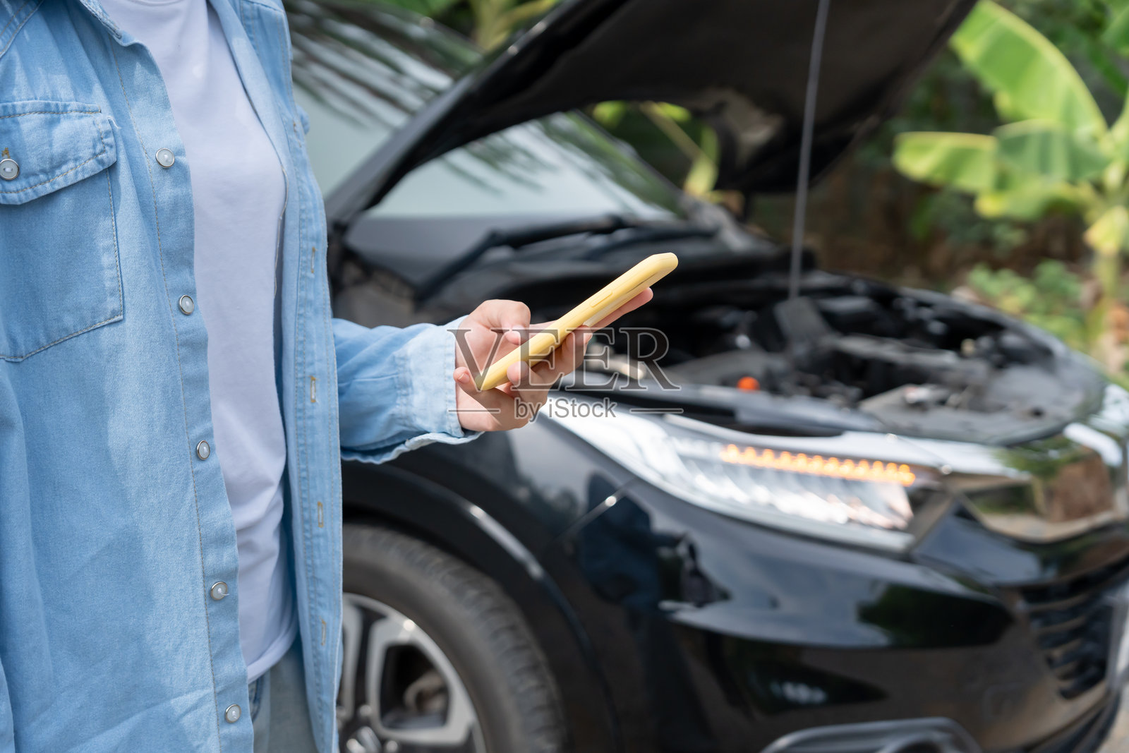 故障，坏车，维修。女性通过手机应用检查保险费用，因为发生了车祸。寻找车库修理汽车，在乡村旅行中等待帮助，紧急情况。照片摄影图片
