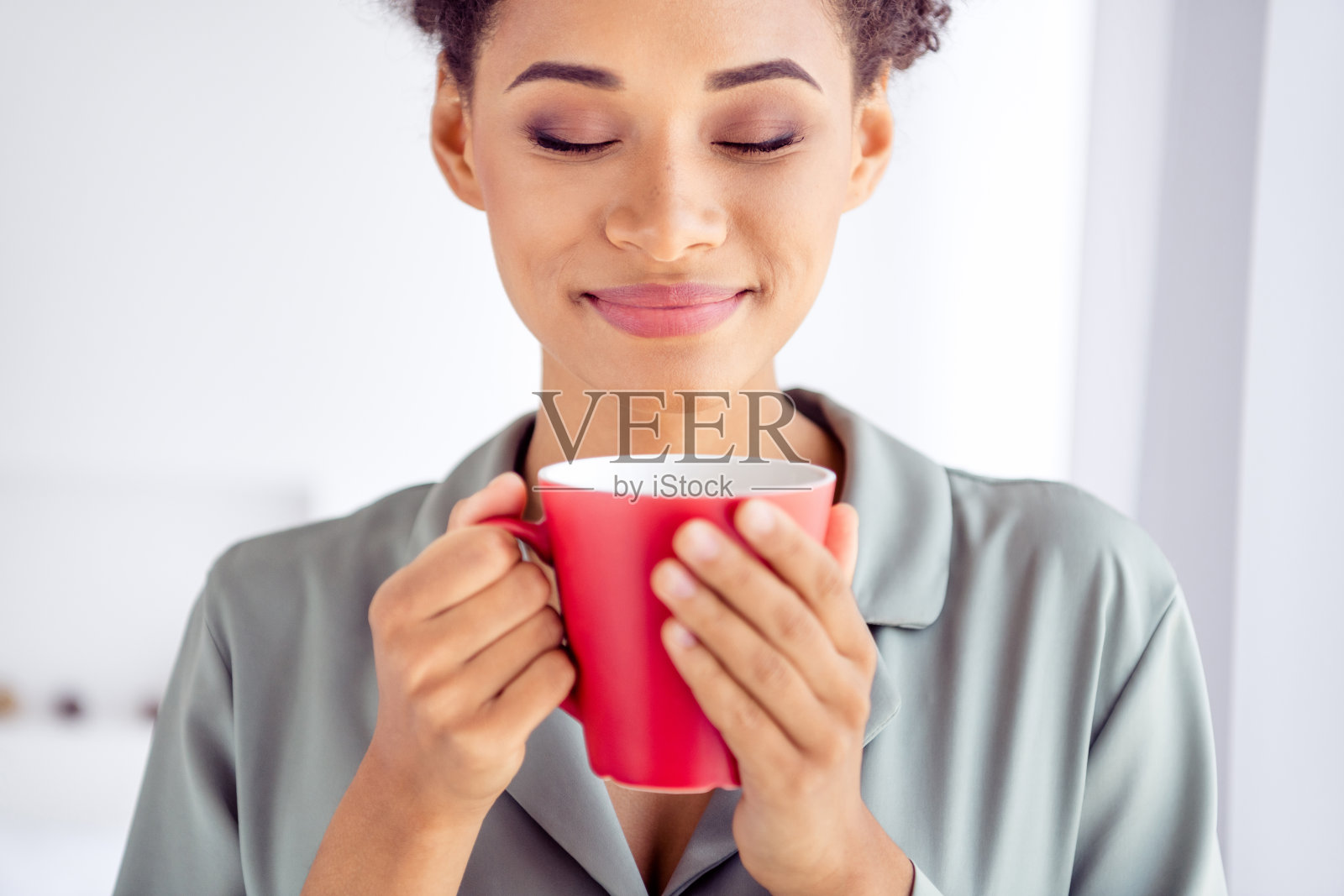 年轻迷人的非洲女性在室内享受美味咖啡的香气，唤醒咖啡因的感觉。照片摄影图片