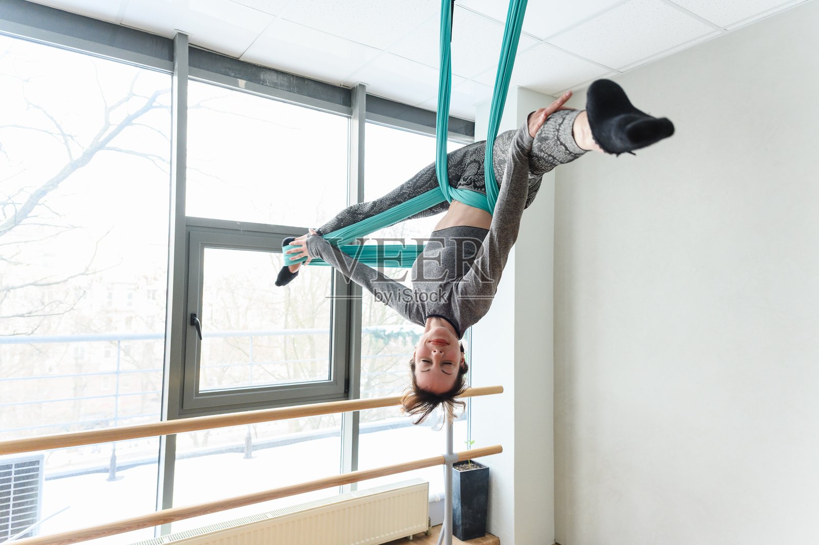 运动女性在青色空中丝带上做倒立姿势。照片摄影图片