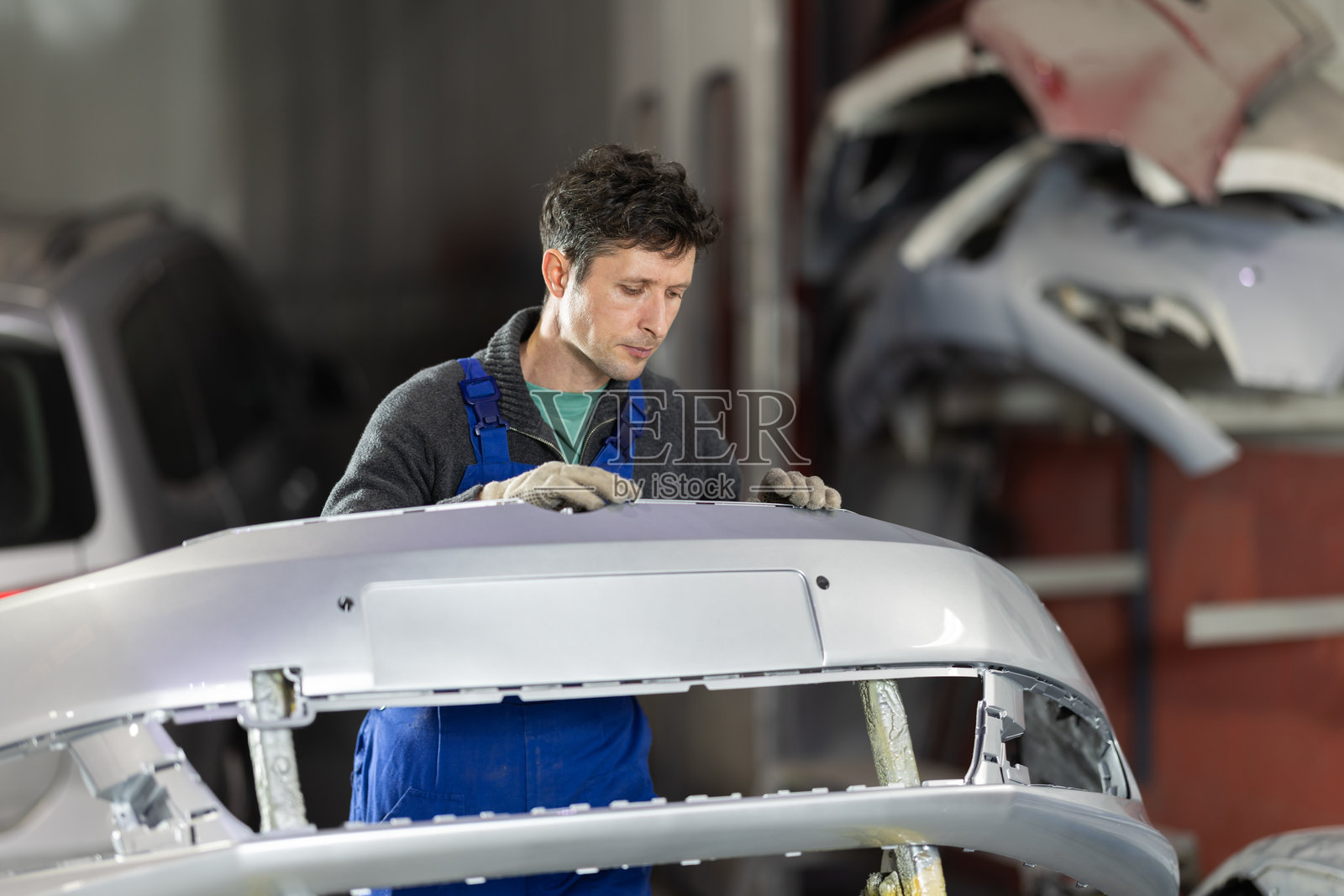 经验丰富的男性汽车修理工在汽车服务中心检查汽车保险杠的喷漆质量照片摄影图片