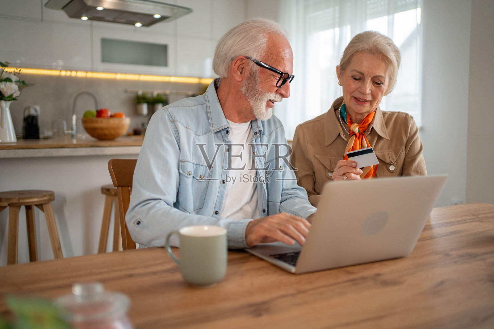 老年夫妇在家中使用笔记本电脑和信用卡进行在线支付照片摄影图片