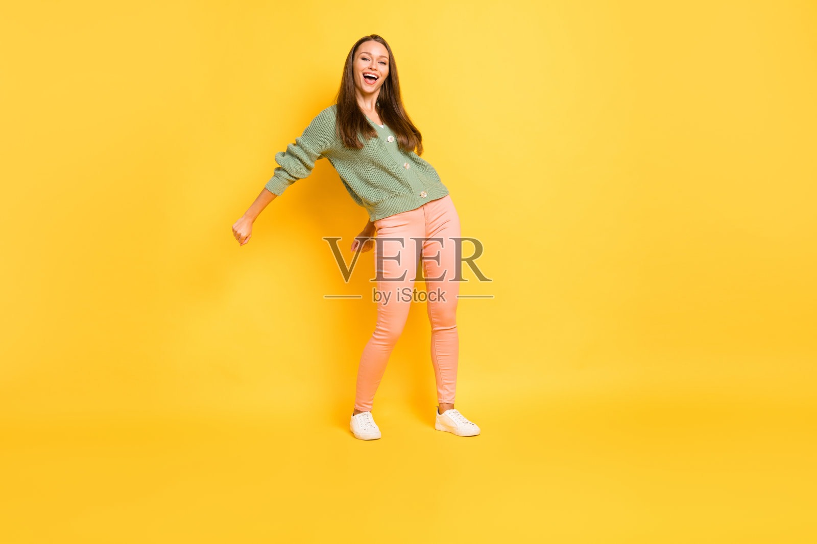 女孩在鲜艳的黄色背景下全身照，正在做现代舞的“Flossing”动作。照片摄影图片