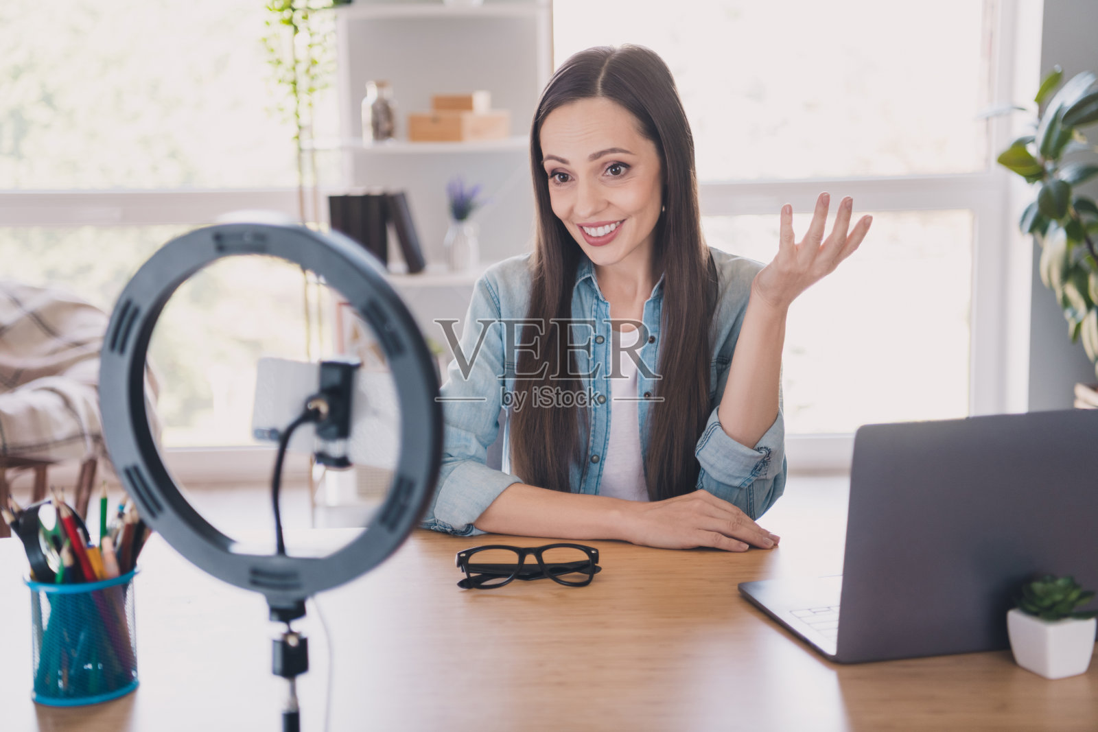 迷人、积极的女性在公寓内拍摄视频，使用手机和环形灯，享受博客创作的时光。照片摄影图片