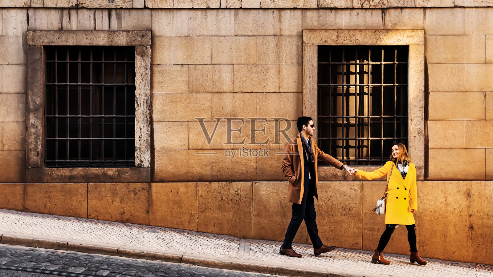 一对游客情侣在街上漫步，身穿时尚服装的年轻女性和男性在城市观光，欣赏周围的景色。照片摄影图片