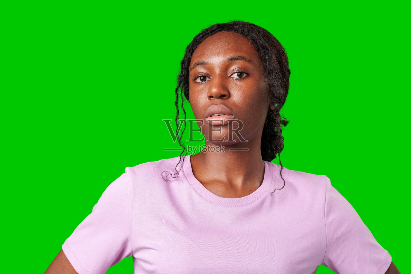 年轻女性在明亮的绿色背景前摆出沉思的表情照片摄影图片