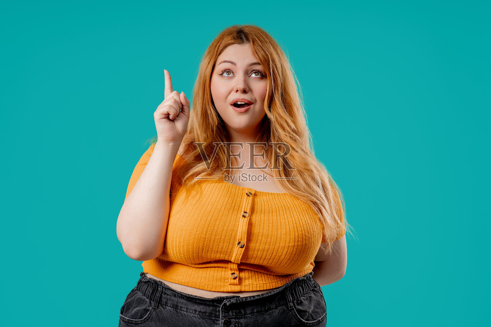 惊讶的胖模特，哇的创意效果，发现的反应。兴奋的女士指向上方。照片摄影图片