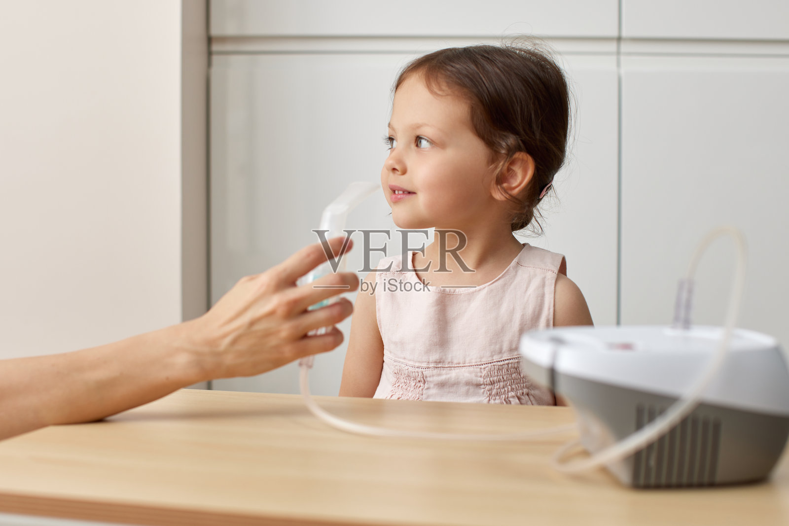可爱的小女孩自己拿着雾化器吸入药物照片摄影图片