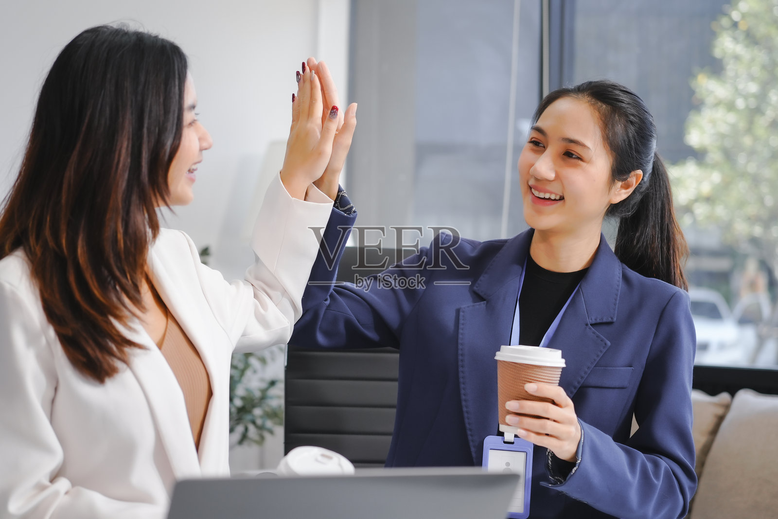 两位亚洲女性商务人士坐在桌前，讨论商业投资。她们分析财务数据，探索市场机会，并制定战略增长计划，以最大化回报，确保商业成功。照片摄影图片