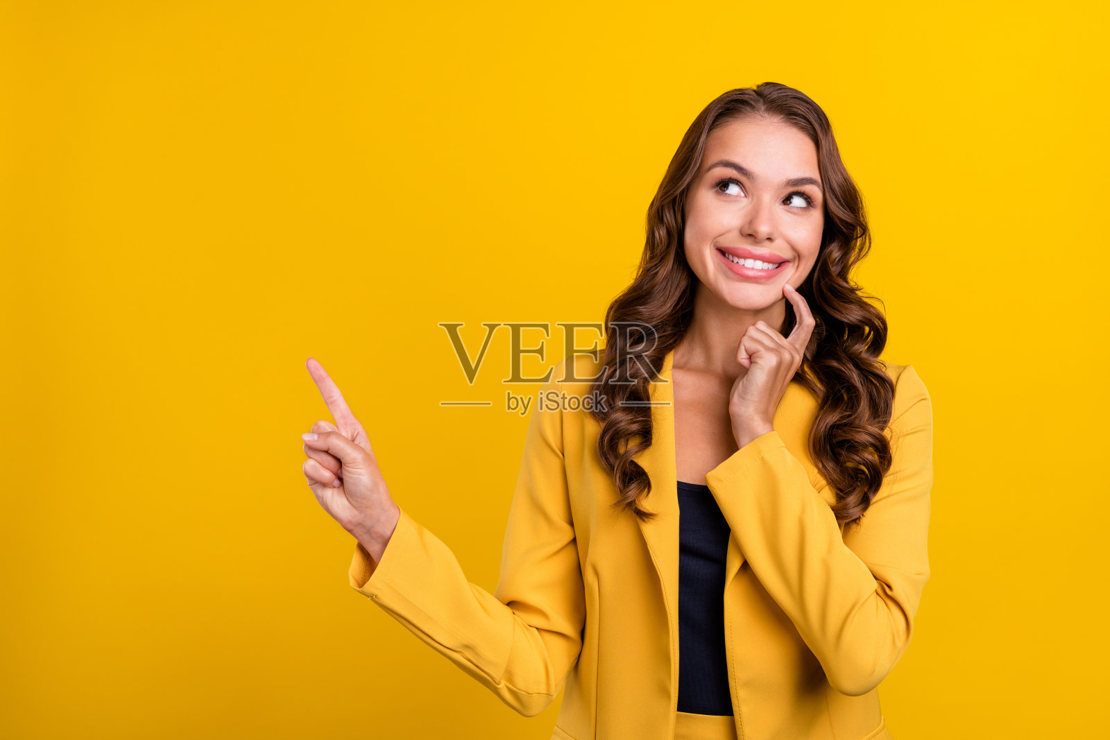 迷人、开朗、好奇的波浪卷发女性在明亮的黄色背景上展示空白空间。照片摄影图片