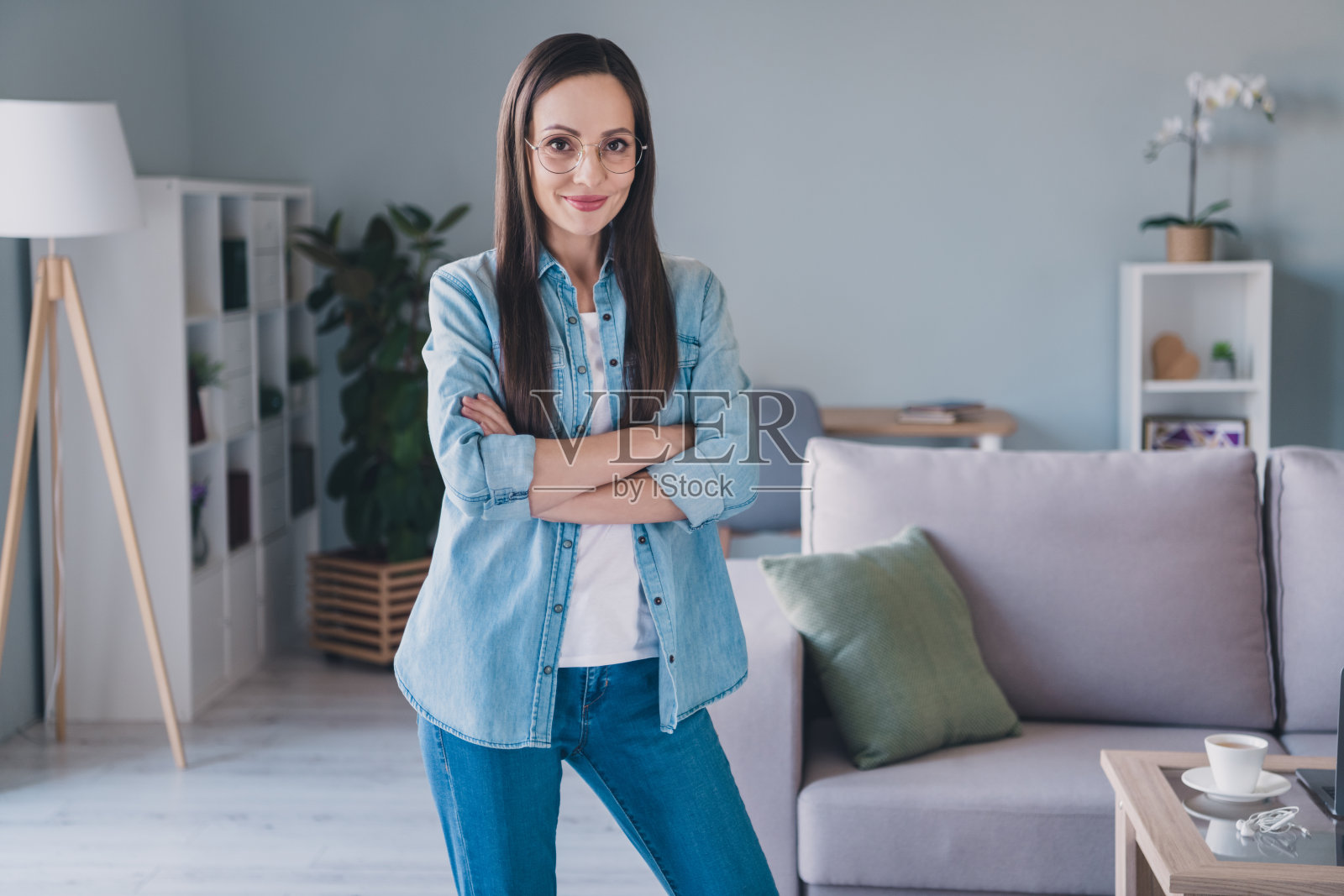 一位迷人、快乐的长发女性专家员工，双臂交叉，安全地待在室内家中。照片摄影图片