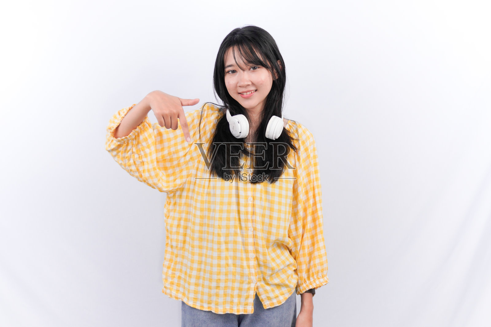 穿着黄色格子衬衫的印尼亚洲女性微笑着并指向下方照片摄影图片