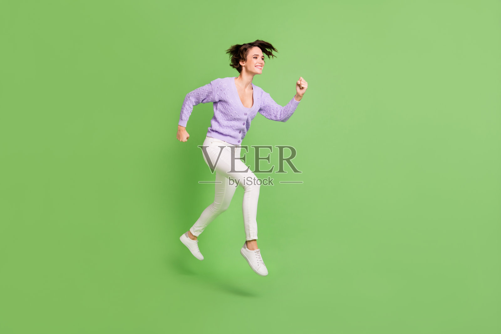 全身照，漂亮快乐的人在绿色背景下奔跑，面带灿烂的笑容，显得空旷。照片摄影图片