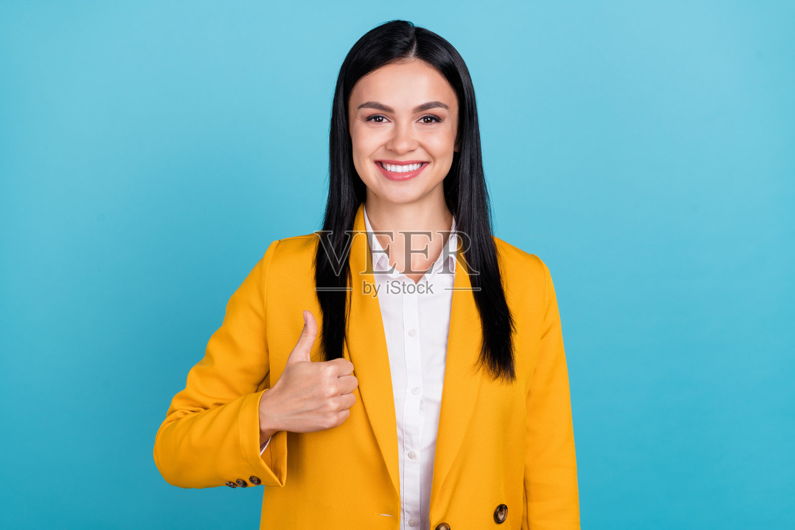 酷炫迷人的漂亮女商人竖起大拇指表示赞同，背景为蓝色。照片摄影图片