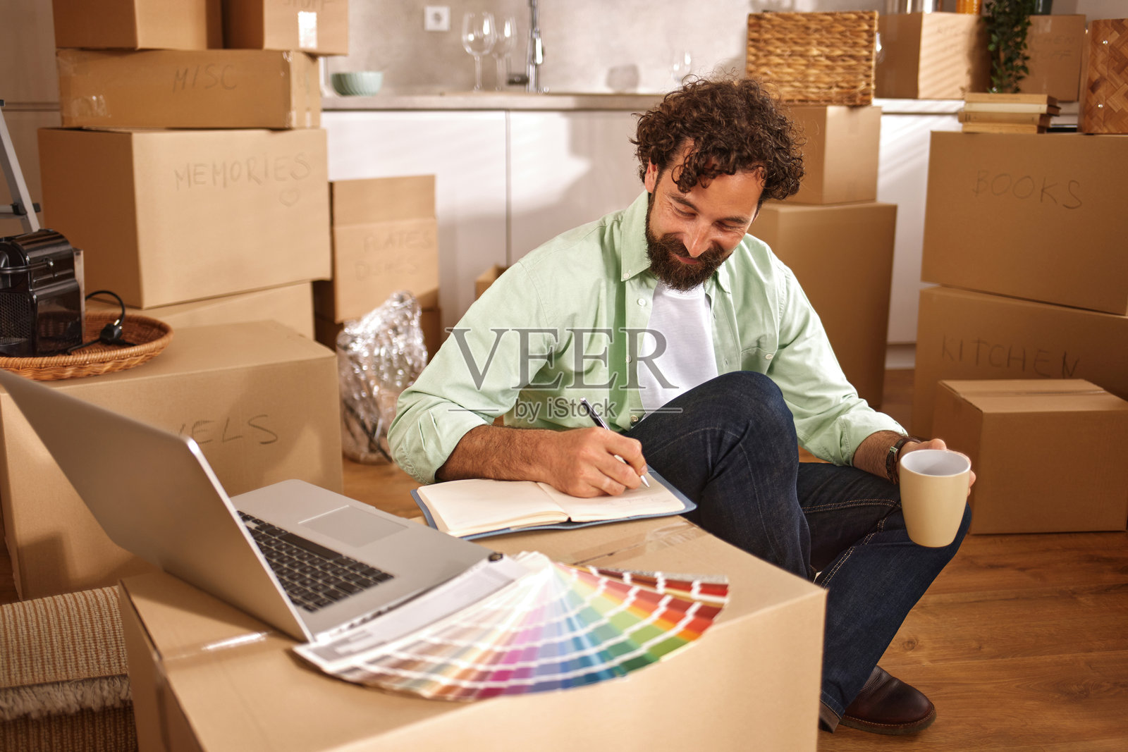 男人在新家中规划装修，周围堆满了箱子照片摄影图片