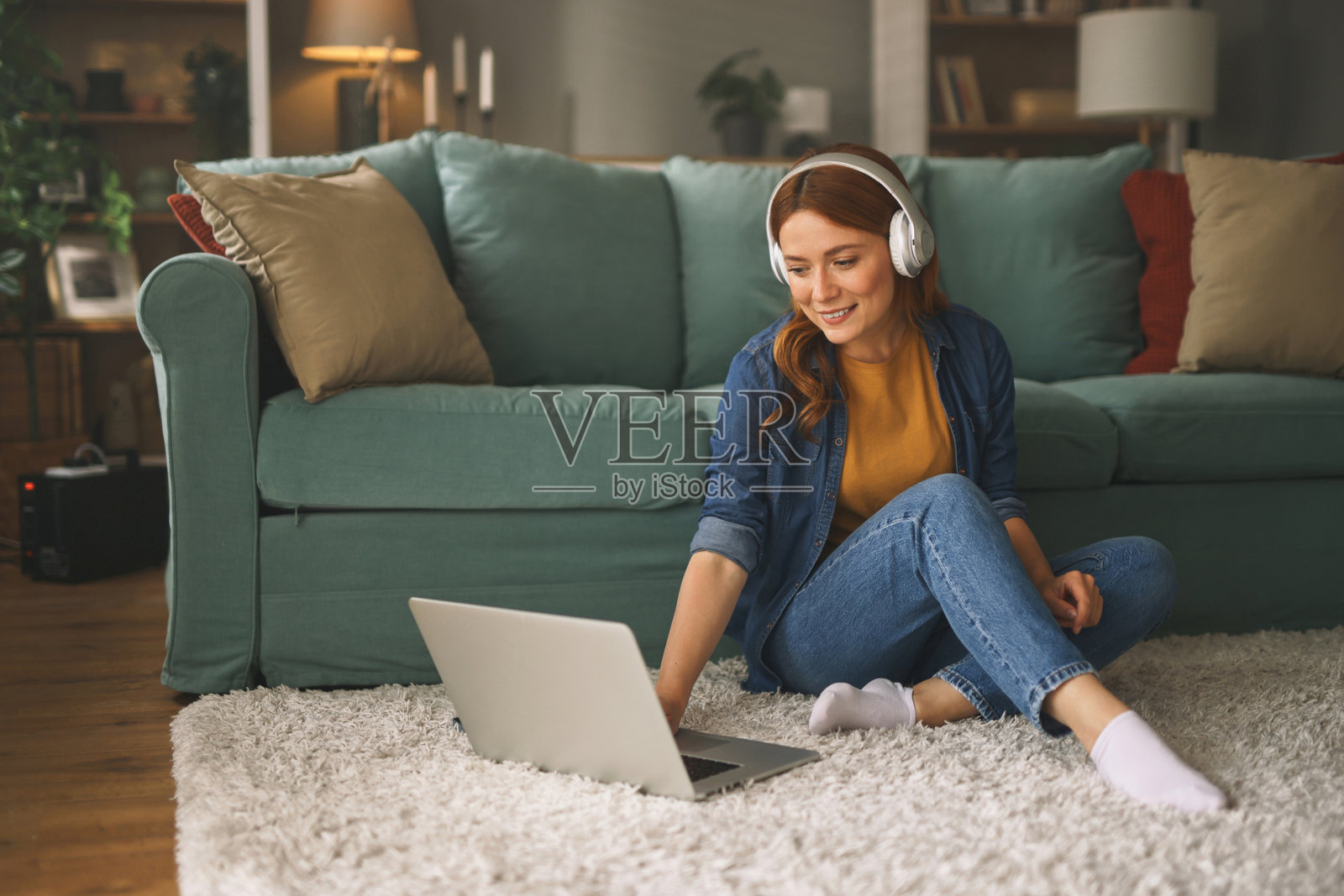 年轻女性在家中使用笔记本电脑和耳机工作照片摄影图片