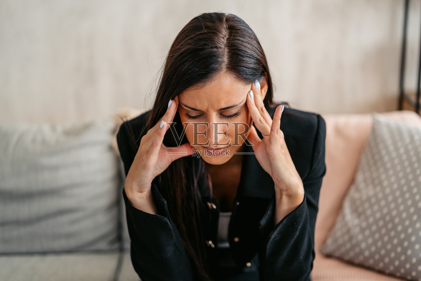 疲惫的年轻女商人在家沙发上坐着，感到头痛照片摄影图片