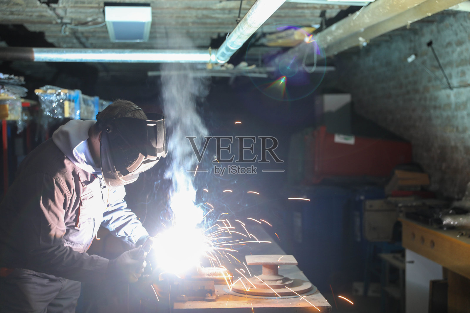 工业工人在昏暗的车间里焊接金属照片摄影图片