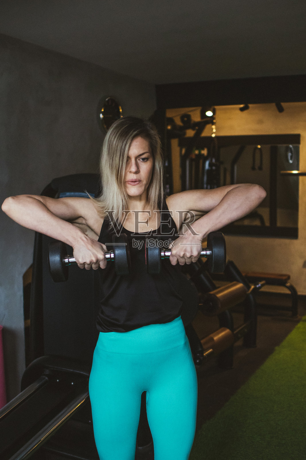 迷人的金发女运动员在健身房进行力量训练。运动员在锻炼过程中举重。照片摄影图片