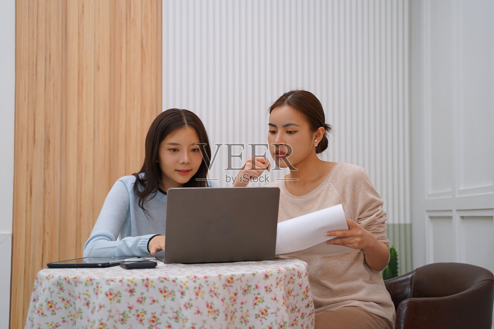 一位女性和朋友在家中使用数字设备。照片摄影图片