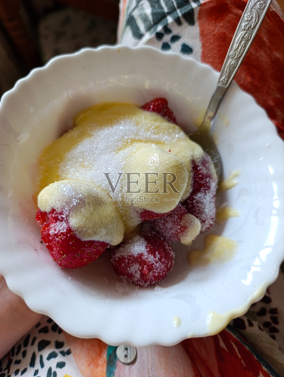 白色碗里装满了草莓和酸奶油，旁边有一把勺子照片摄影图片