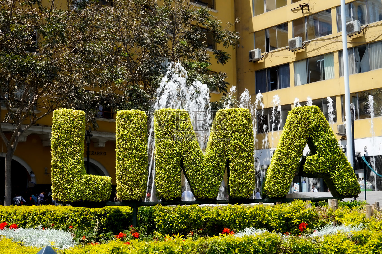 阳光明媚的日子里,秘鲁利马市中心的繁忙广场上,周围环绕着喷泉和鲜花的大型绿色“LIMA”标志。照片摄影图片