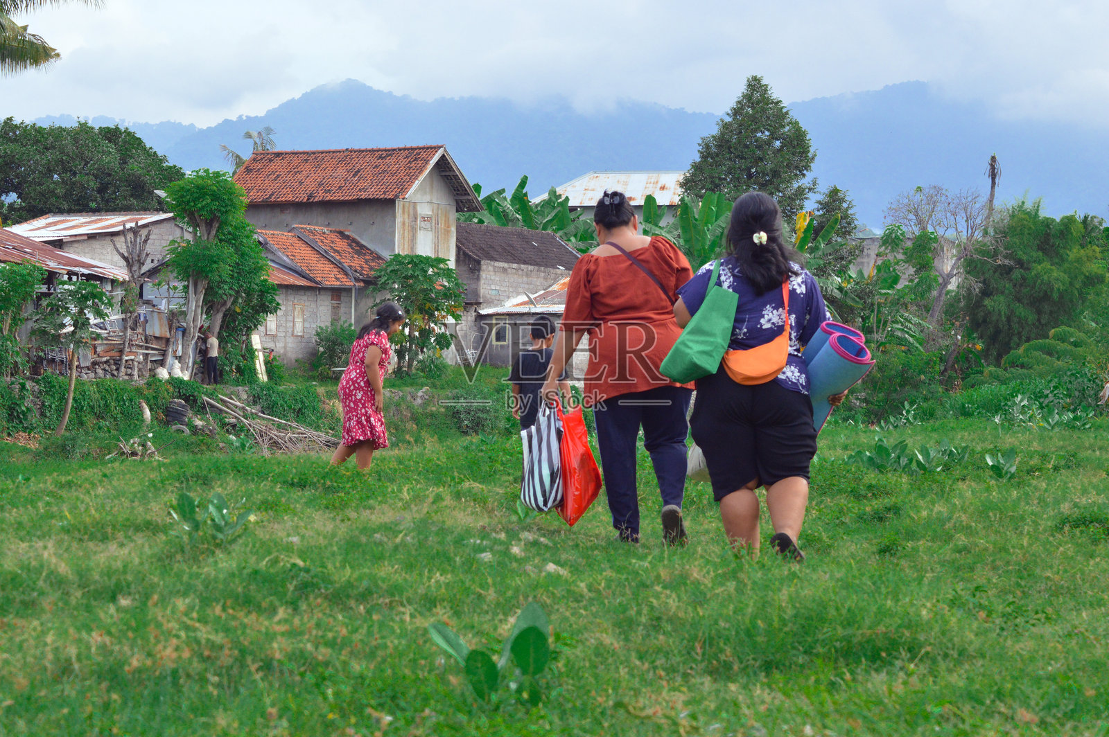 孩子们在前面走，妈妈们在后面提着物品。照片摄影图片