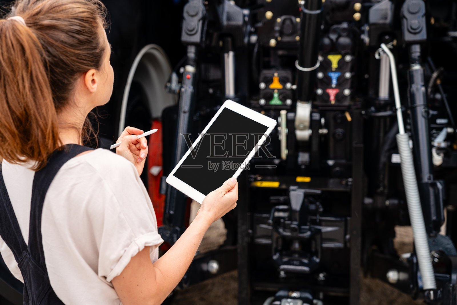 女性技术人员在农场设备现场使用数字平板检查拖拉机照片摄影图片