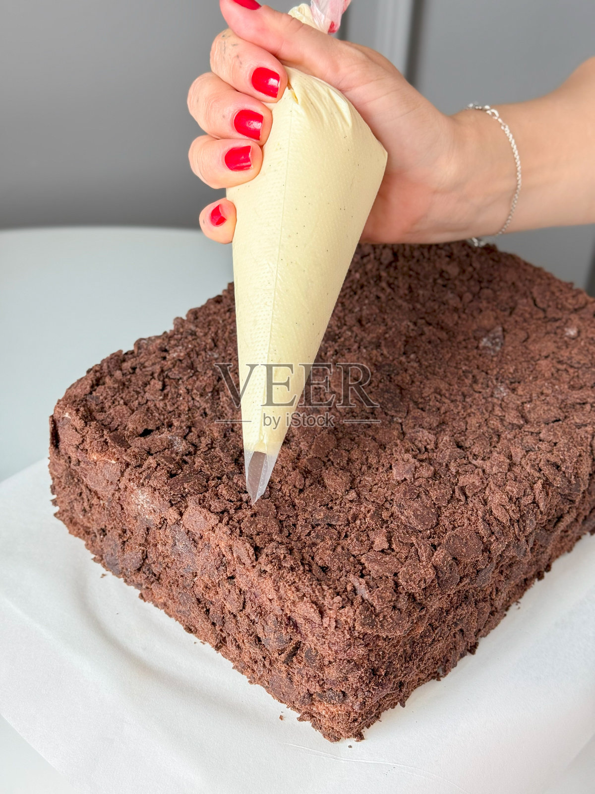 手握裱花袋在巧克力碎屑蛋糕上照片摄影图片