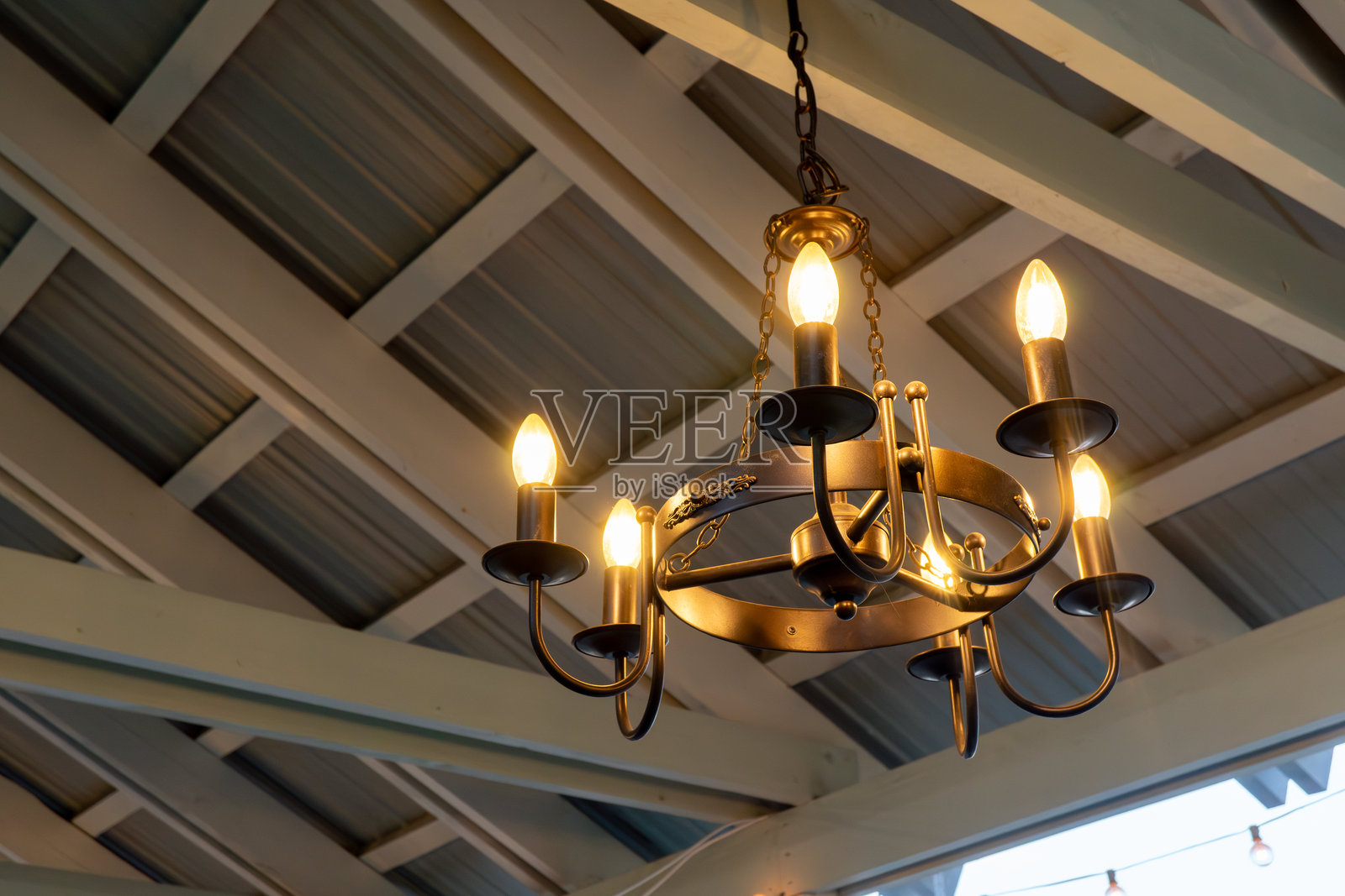 古朴的复古吊灯悬挂在木梁天花板上，温暖的灯泡照亮了整个空间照片摄影图片